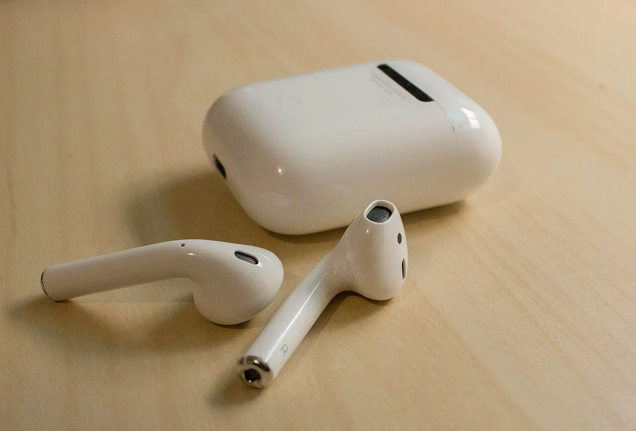 木の机に置かれた初代 AirPods と充電ケース