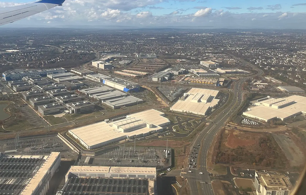 米バージニア州ラウドン郡アッシュバーン付近の空撮。大型のデータセンター群と変電設備が商業施設や住宅地と混在している（2025年11月撮影）