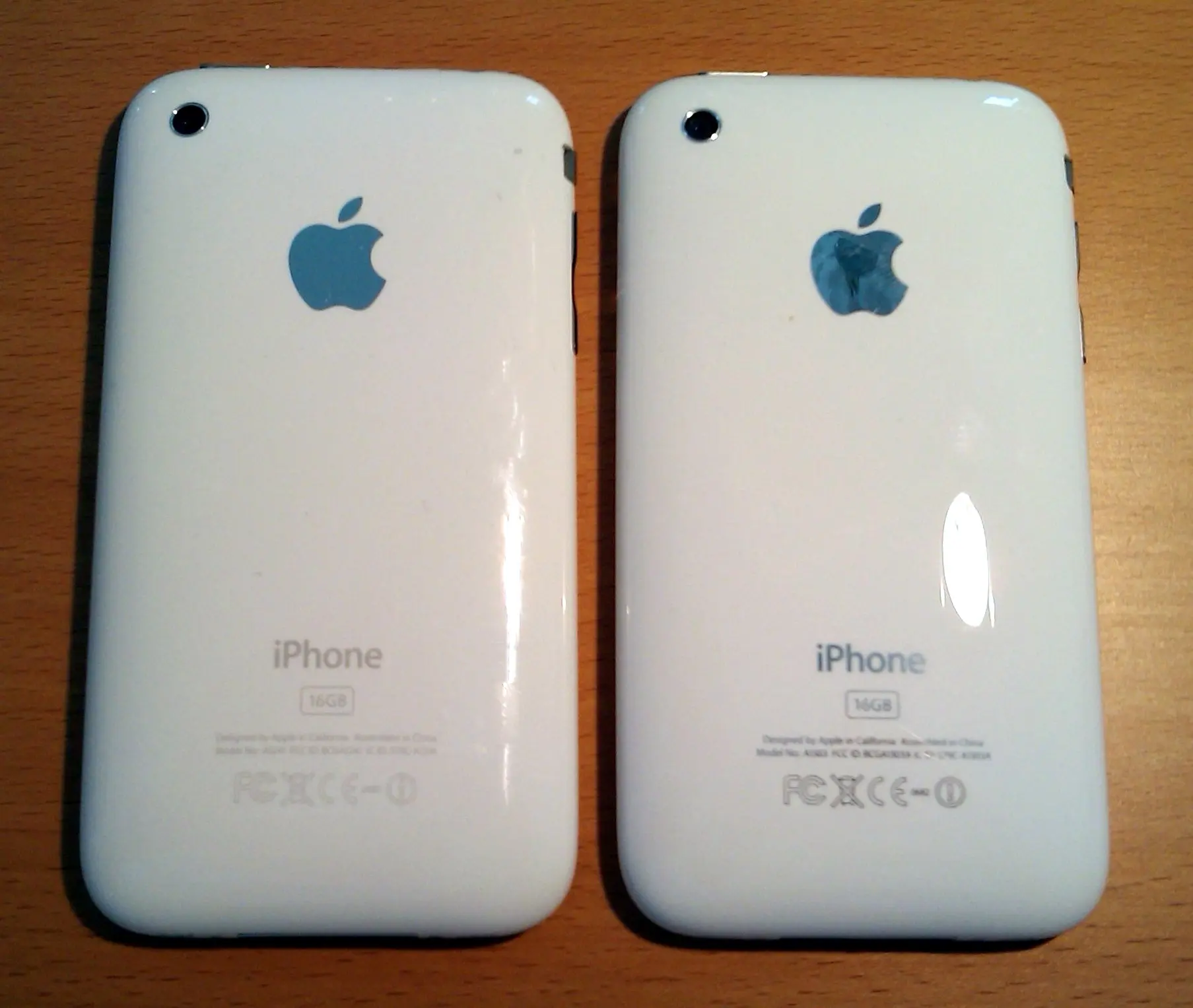 The backs of a white 16 GB iPhone 3G (left) and iPhone 3GS (right) side by side on a wooden desk, photographed on 19 June 2009