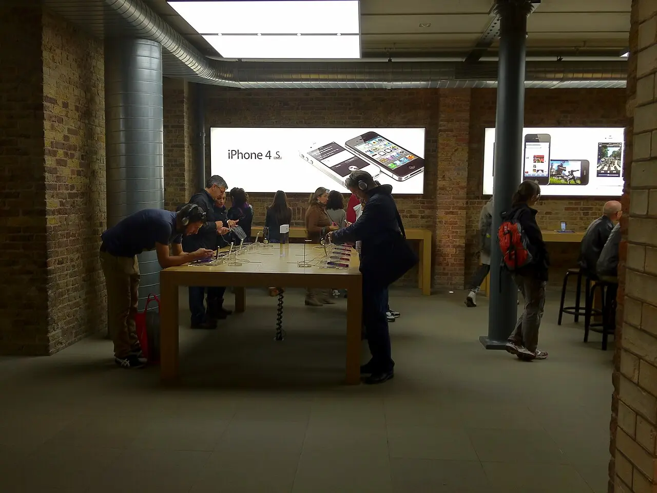 発売直後の Apple Store で iPhone 4S の実機を試す来店客。奥の壁面に「iPhone 4S」の告知が掲げられている
