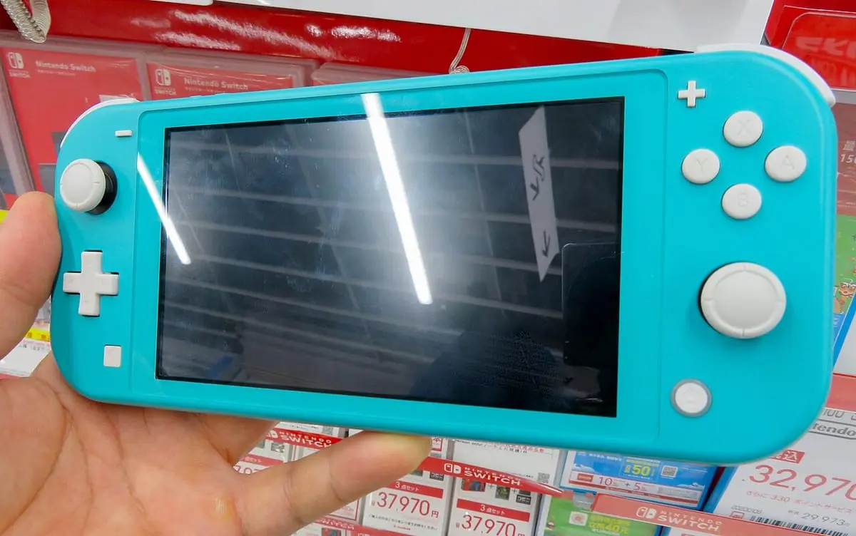 A turquoise Nintendo Switch Lite held in one hand, with the sticks, D-pad and ABXY buttons built in on either side of the screen