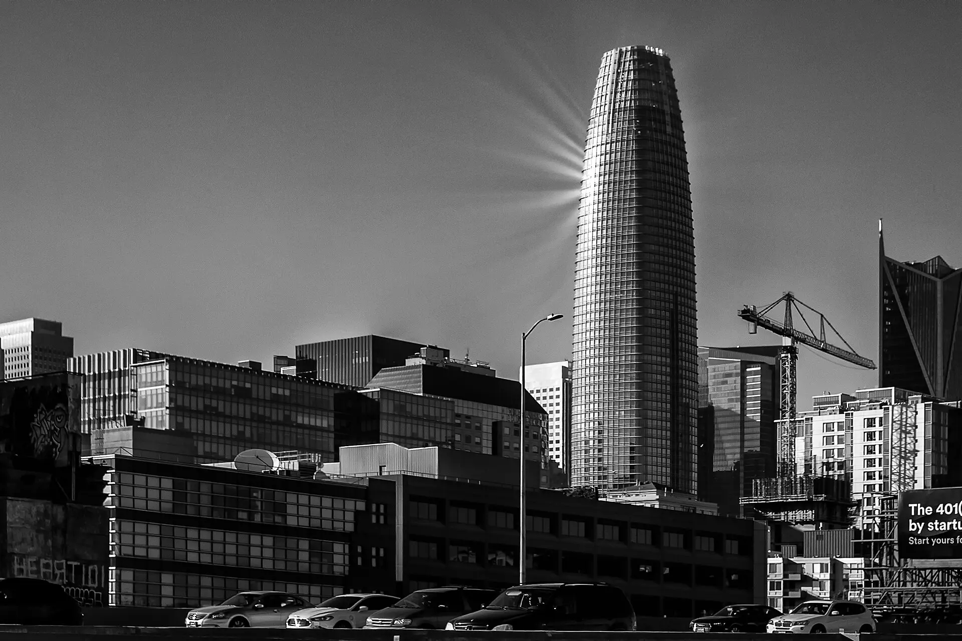 Black-and-white photograph of Salesforce Tower rising over the San Francisco skyline, taken in 2019. The tower was completed in 2018, long after the 1999 founding
