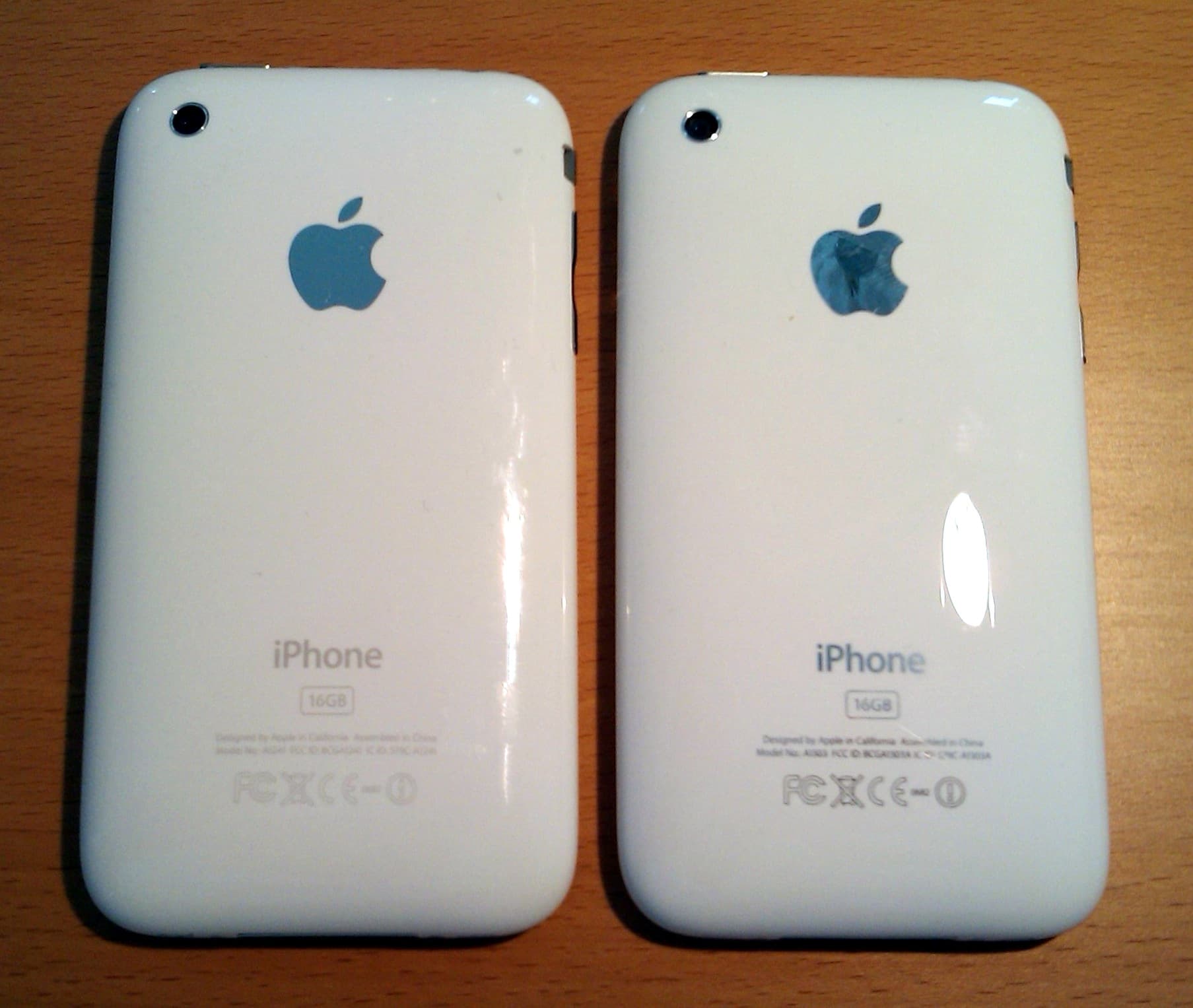 The backs of a white 16 GB iPhone 3G (left) and iPhone 3GS (right) side by side on a wooden desk, photographed on 19 June 2009